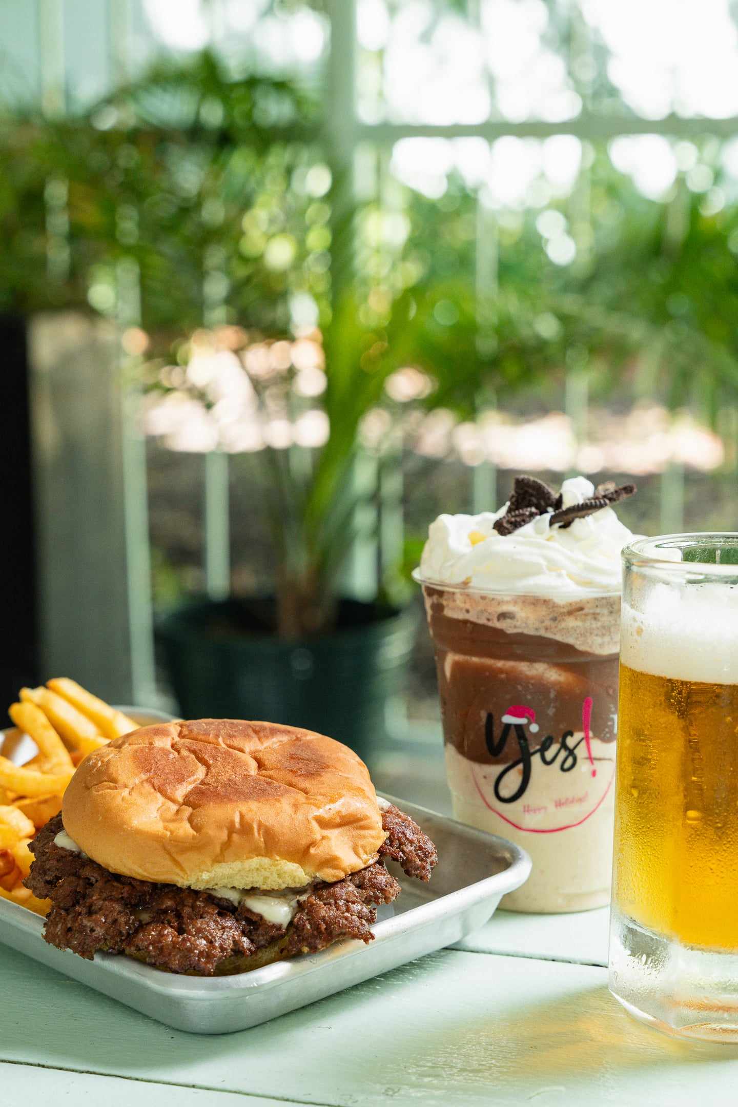 A smash burger with fries, a caramel shake and a glass of beer on a tray