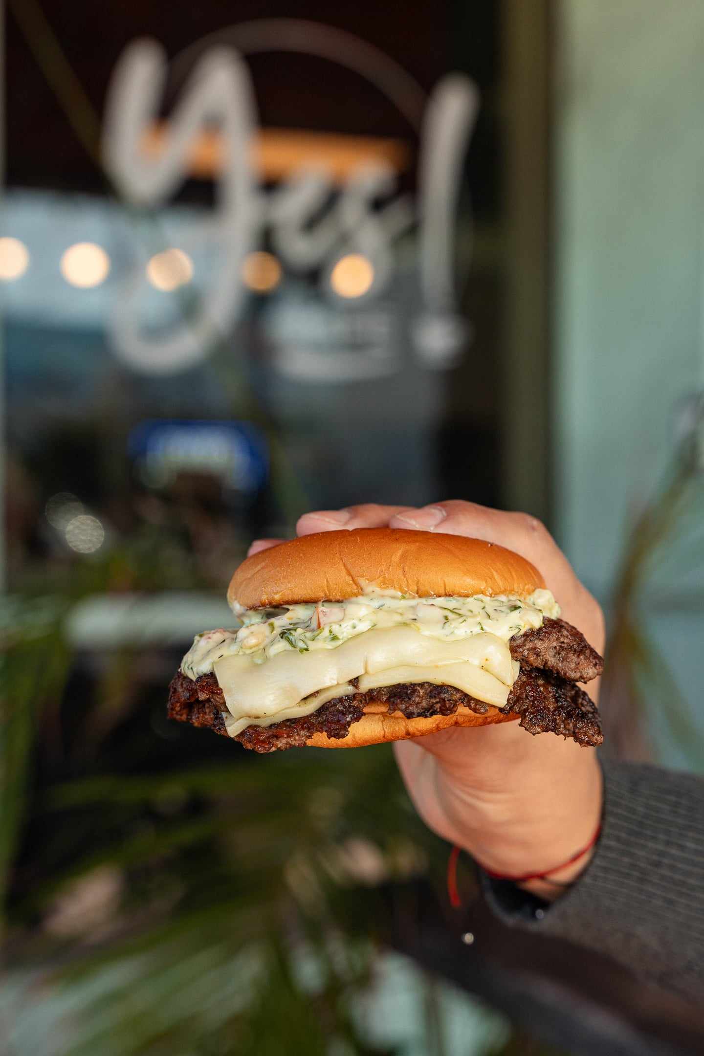 A smash burger with melted cheese on a brioche bun held in two hands