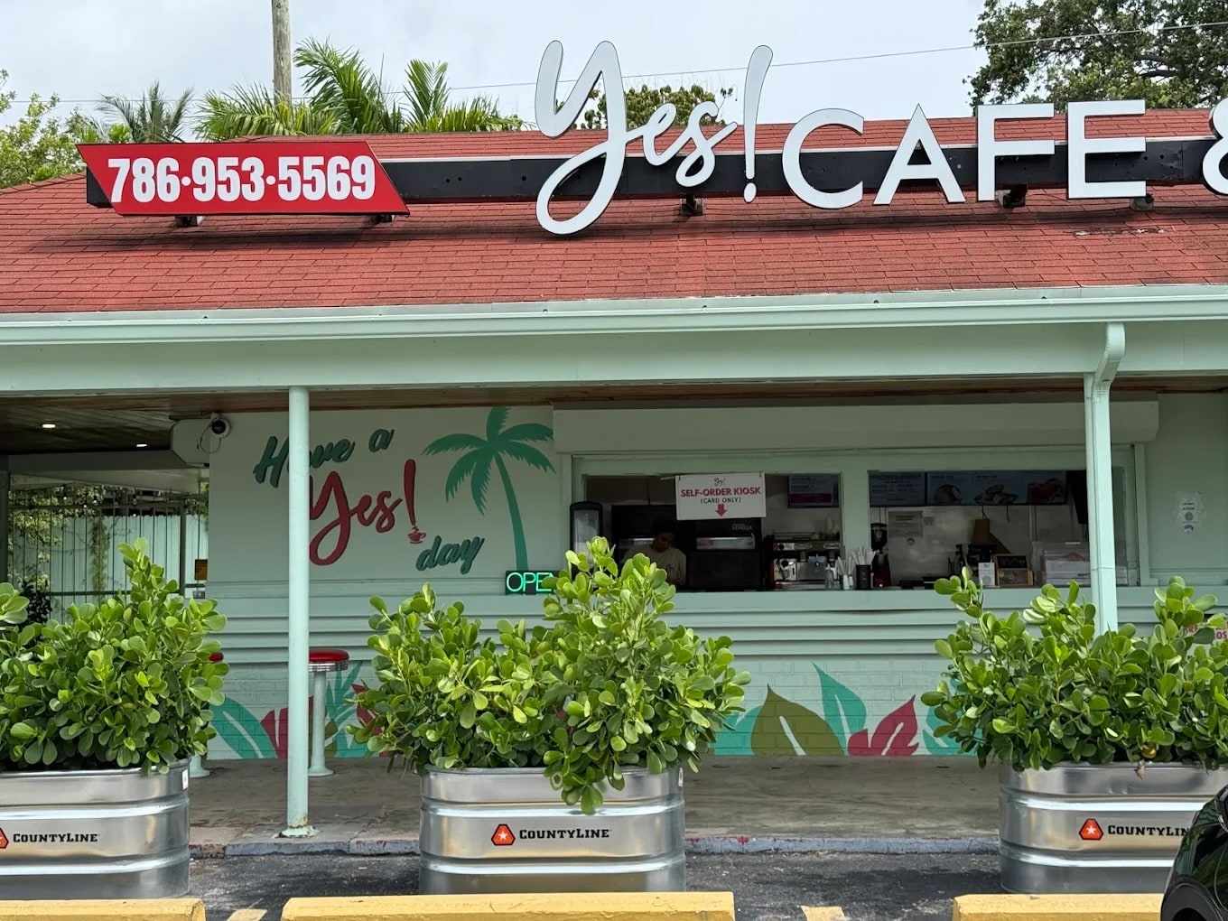 YES! Cafe & Pizza storefront at 731 NE 79th St: mint-green building, red roof, Yes! CAFE sign and the Have a Yes! day mural